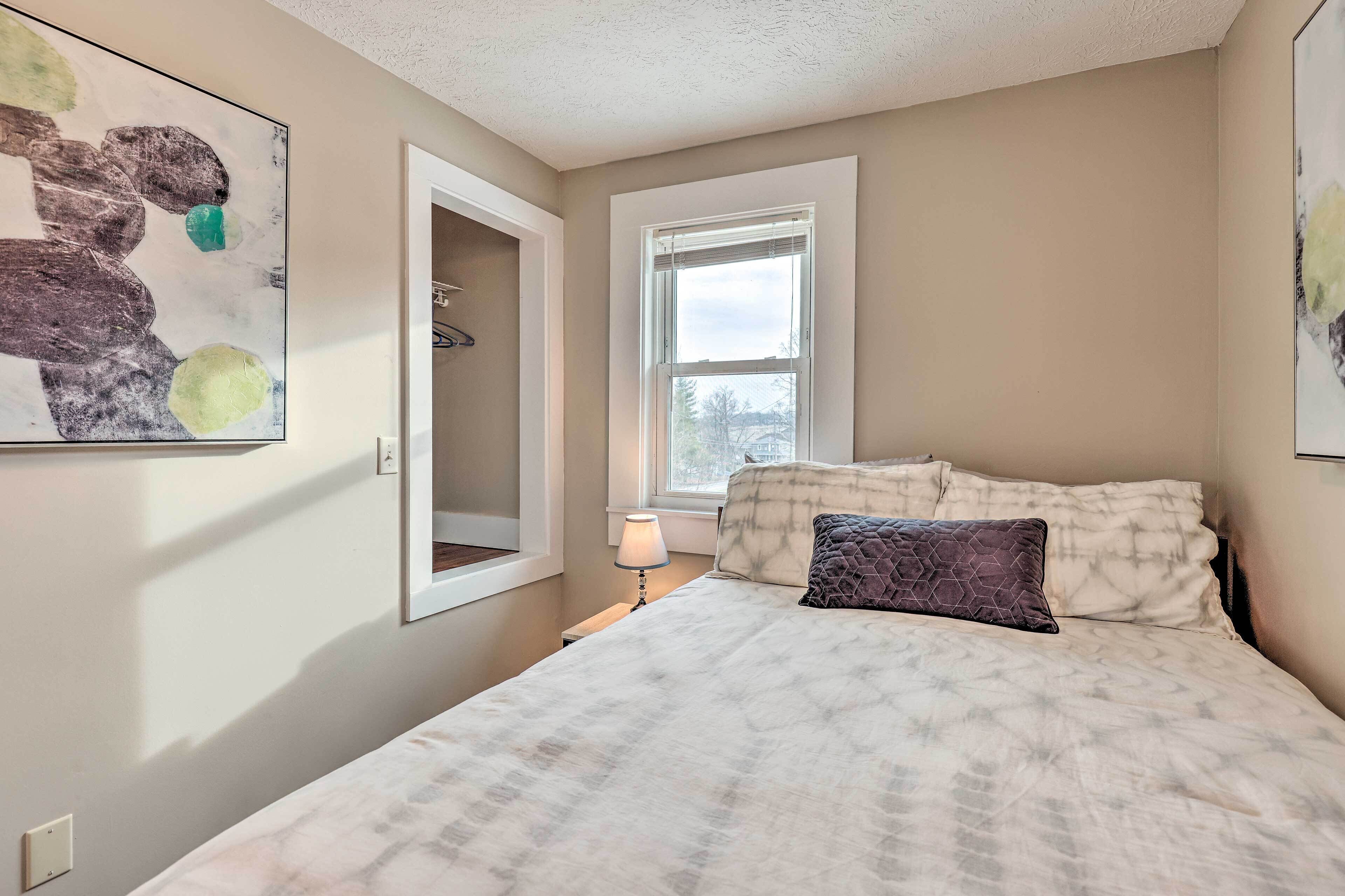 A bedroom with a bed, a window, and a door leading to a closet.
