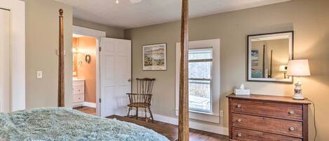 A bedroom with a four-poster bed, a wooden dresser, a chair, and a ceiling fan.