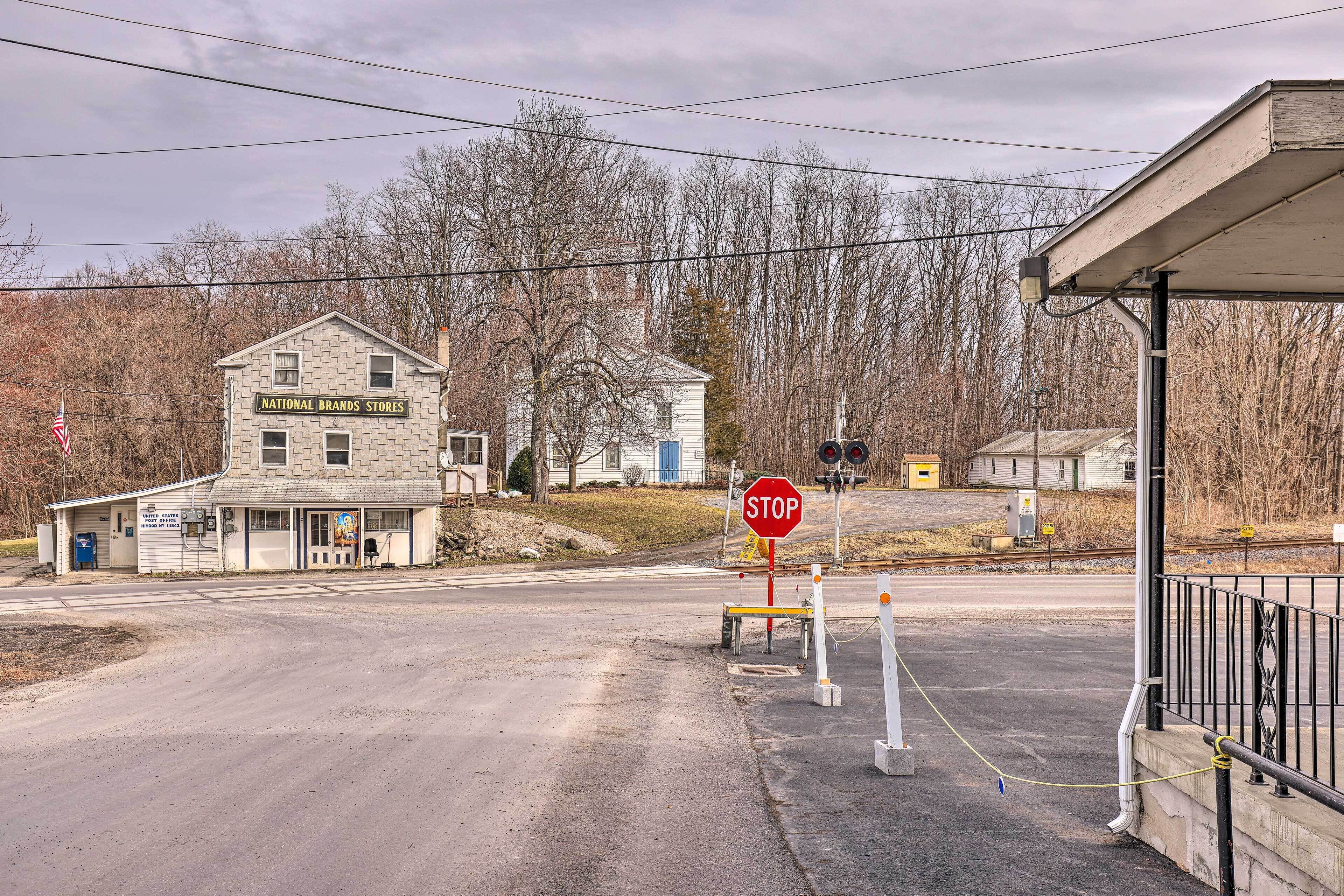 Una intersección rural con una señal de stop, un edificio de National Brands Stores y un cruce de trenes.