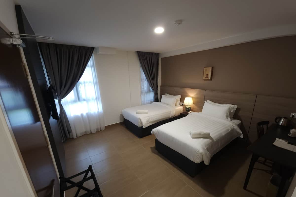 A hotel room with two beds, a desk, a chair, and a TV.