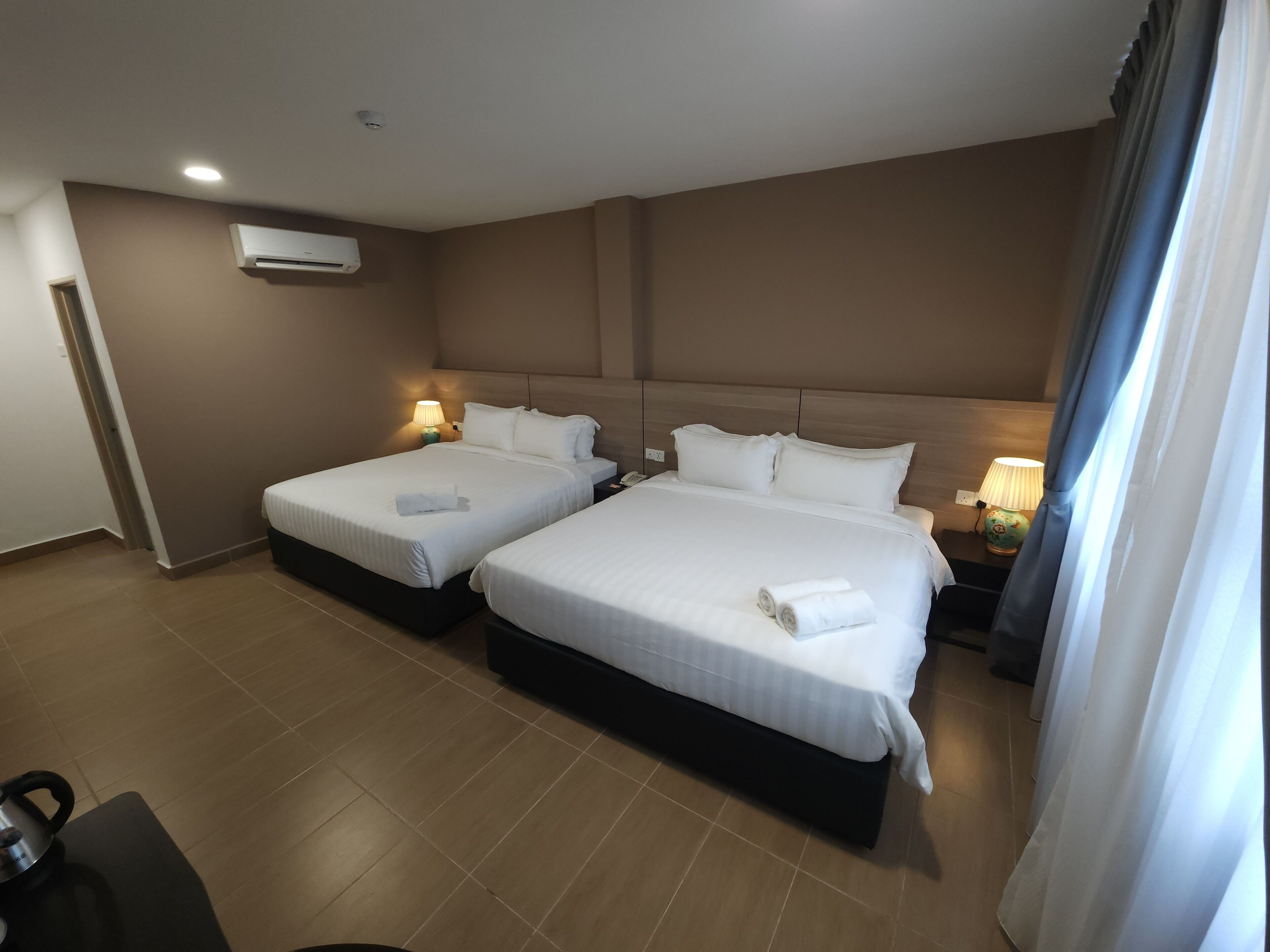 Habitación de hotel con dos camas, un escritorio y una silla.