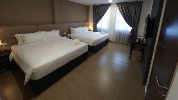 A hotel room with two beds, a desk, a chair, a TV, and a door. - Yu Hotel Chinatown (Kuala Lumpur)