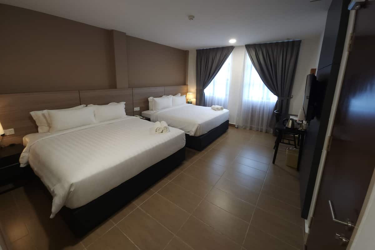 A hotel room with two beds, a desk, a chair, a TV, and a door.