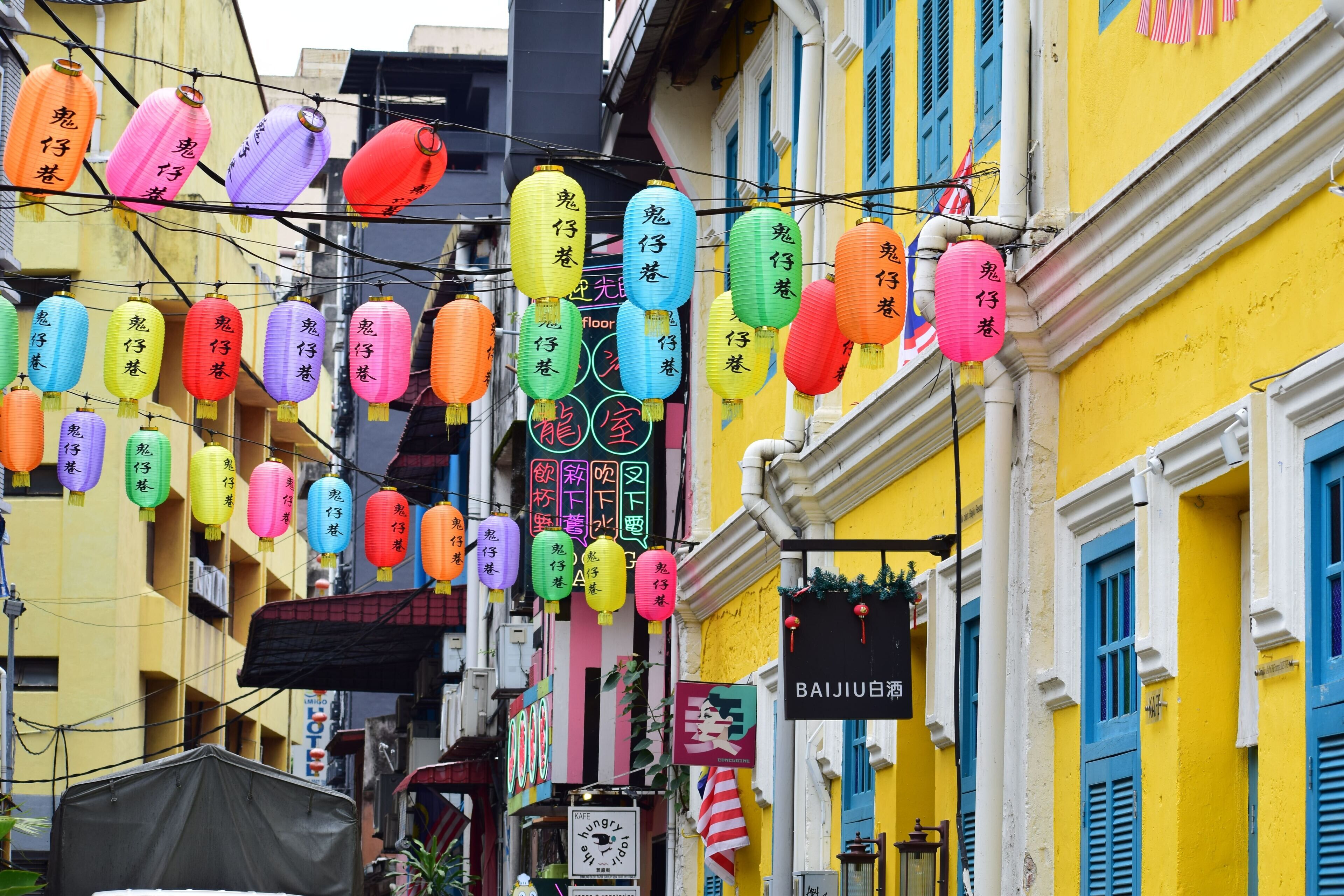 Una calle con faroles y letreros coloridos, que muestra un barrio lleno de vida.