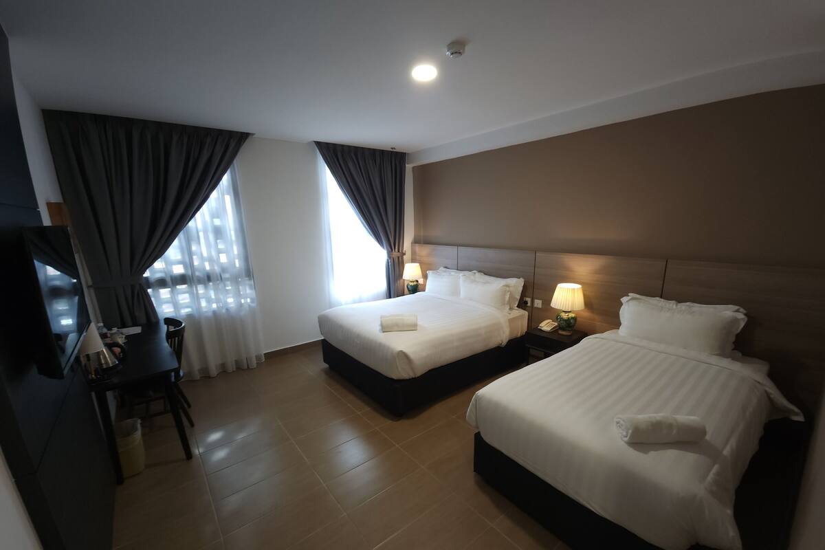 A hotel room with two beds, a desk, and a chair.