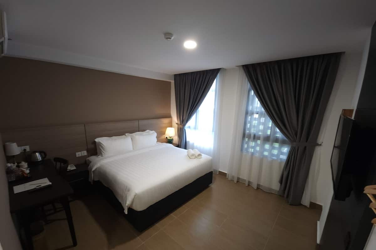A hotel room with a bed, a desk, a lamp, and a TV.