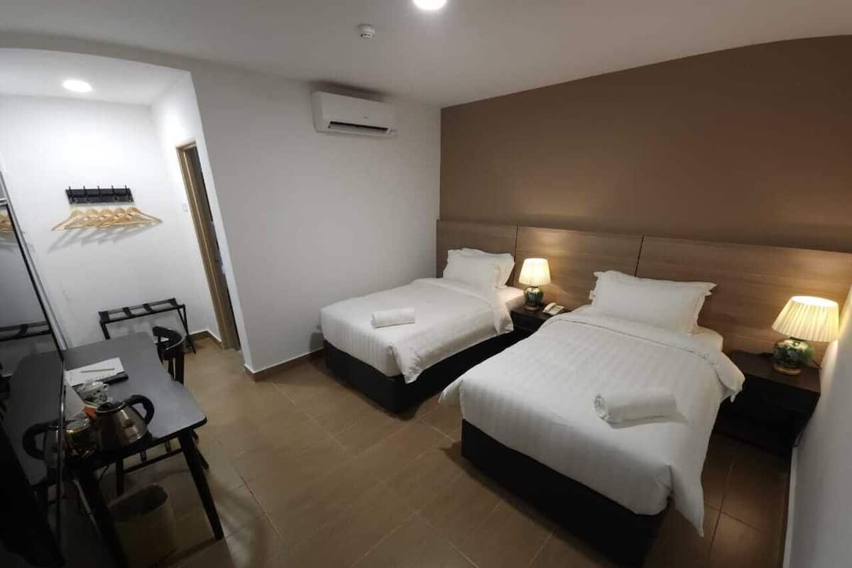 A hotel room with two beds, a desk, and a chair.