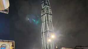 A tall, illuminated skyscraper with a unique design, surrounded by a busy street with pedestrians and vehicles. - Yu Hotel Chinatown (Kuala Lumpur)