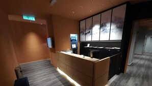 A reception area with a wooden reception desk, a flat-screen TV, and a wall-mounted artwork. - Yu Hotel Chinatown (Kuala Lumpur)