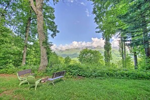 A bench and chair in a forested area with a view of distant mountains.