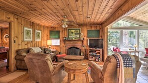 Ein gemütliches Holzhaus-Interieur mit Kamin, bequemen Sitzmöglichkeiten und einem Fernseher.