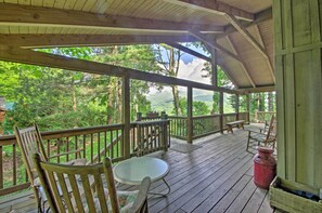 A wooden deck with a table and chairs, overlooking a forested area.