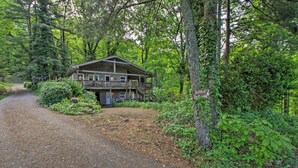 Eine Hütte mit Veranda und überdachter Terrasse, umgeben von dichtem Wald.