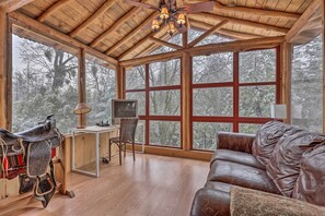 A cozy room with a wooden ceiling, large windows, a leather sofa, a mounted TV, and a saddle. - Creekside Cabin 8 Mi to Kings Canyon National Park (Miramonte)