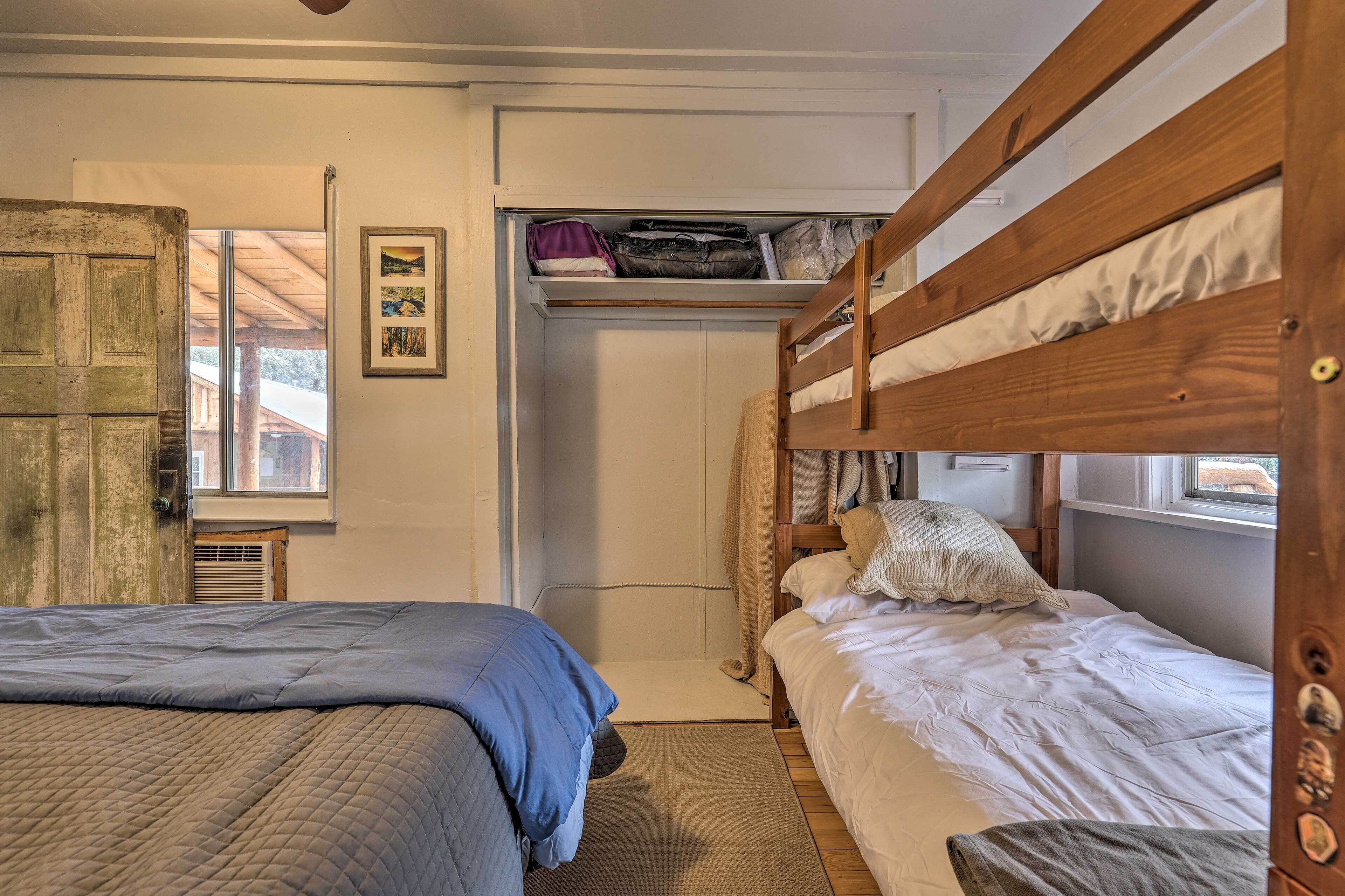 A bedroom with two beds, a wooden door, a window, and a closet with shelves.