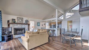 A spacious living room with a fireplace, a television, and a dining area with metal chairs and a table.