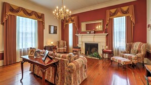 A traditional living room with a fireplace, patterned armchairs, and a wooden floor. - Historic 1840's Estate on 20 Acres w/ Guest House (Lafayette)