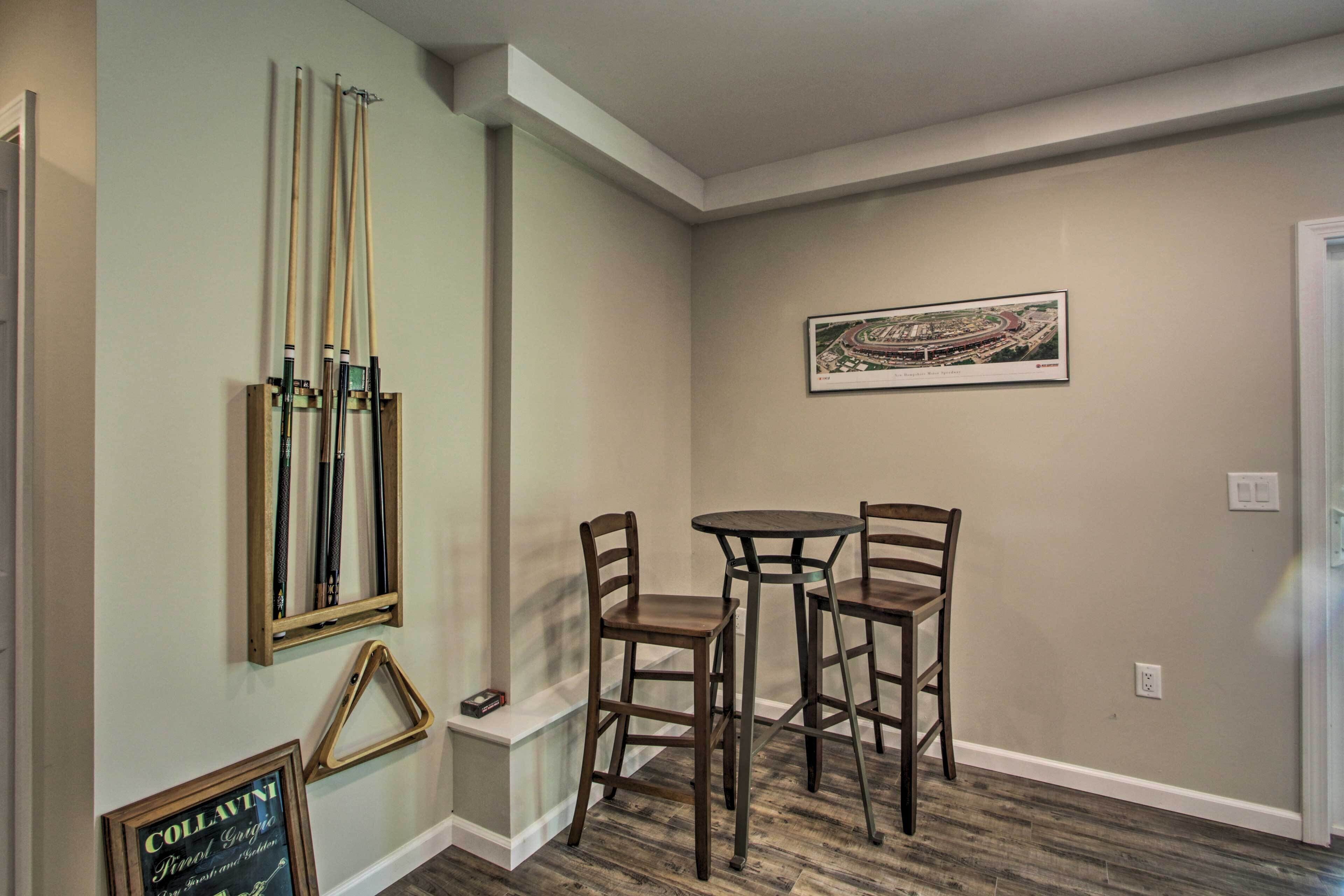 Une pièce avec une table de billard, des chaises et un tableau encadré au mur.