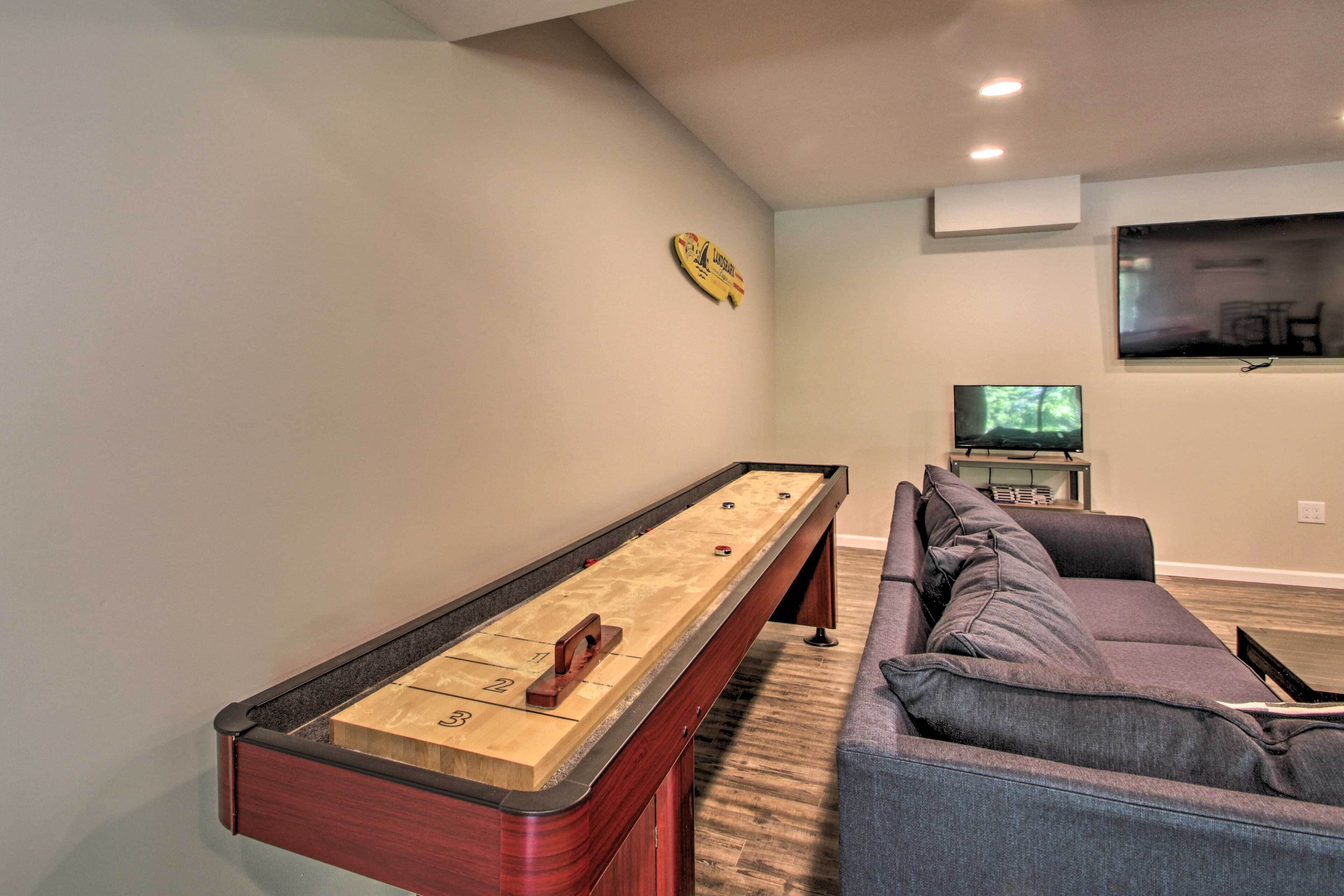 Ein Zimmer mit Shuffleboard-Tisch, einer Couch und einem Fernseher.