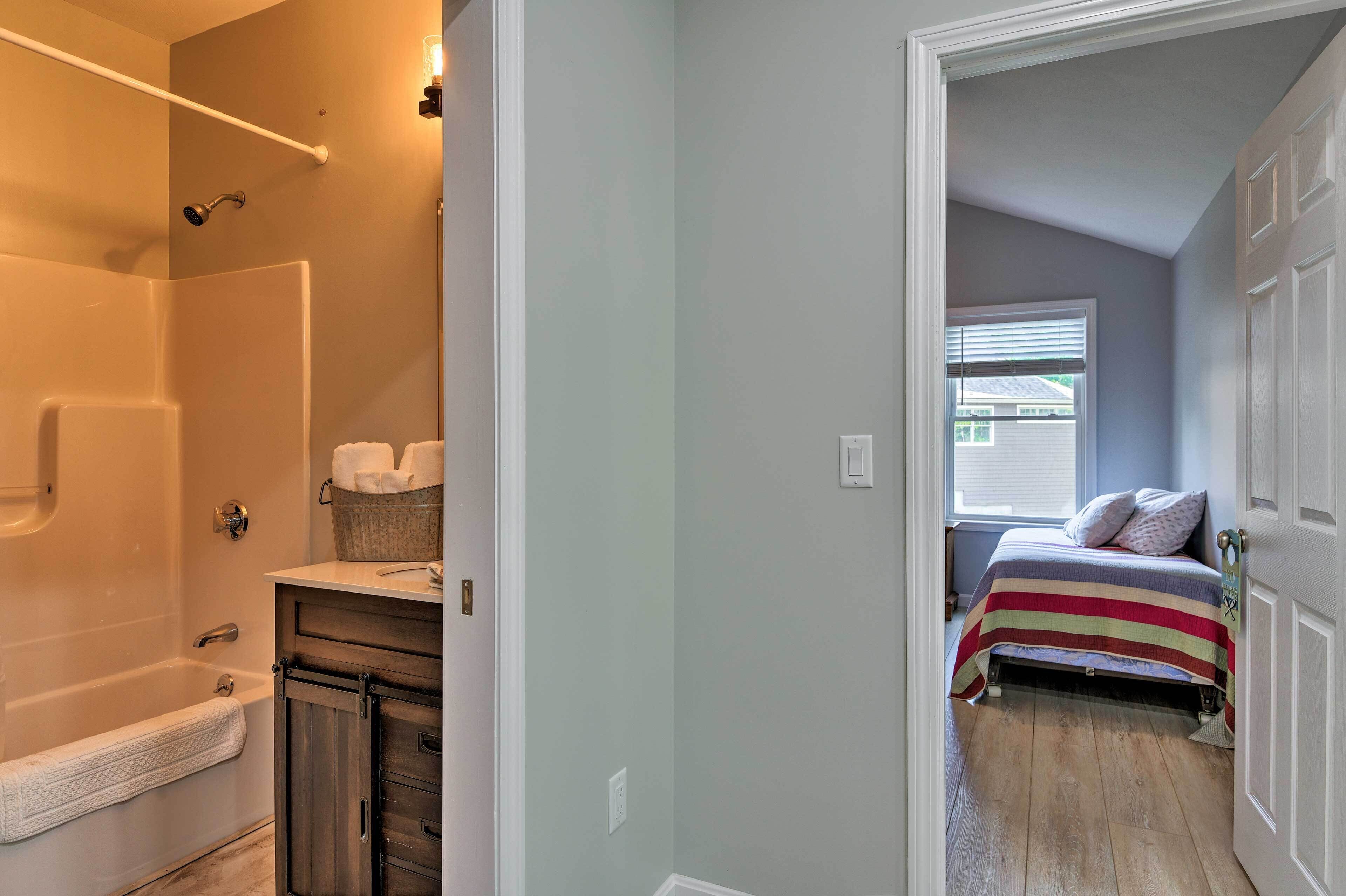 A bathroom with a bathtub, a shower, and a vanity with a towel rack.