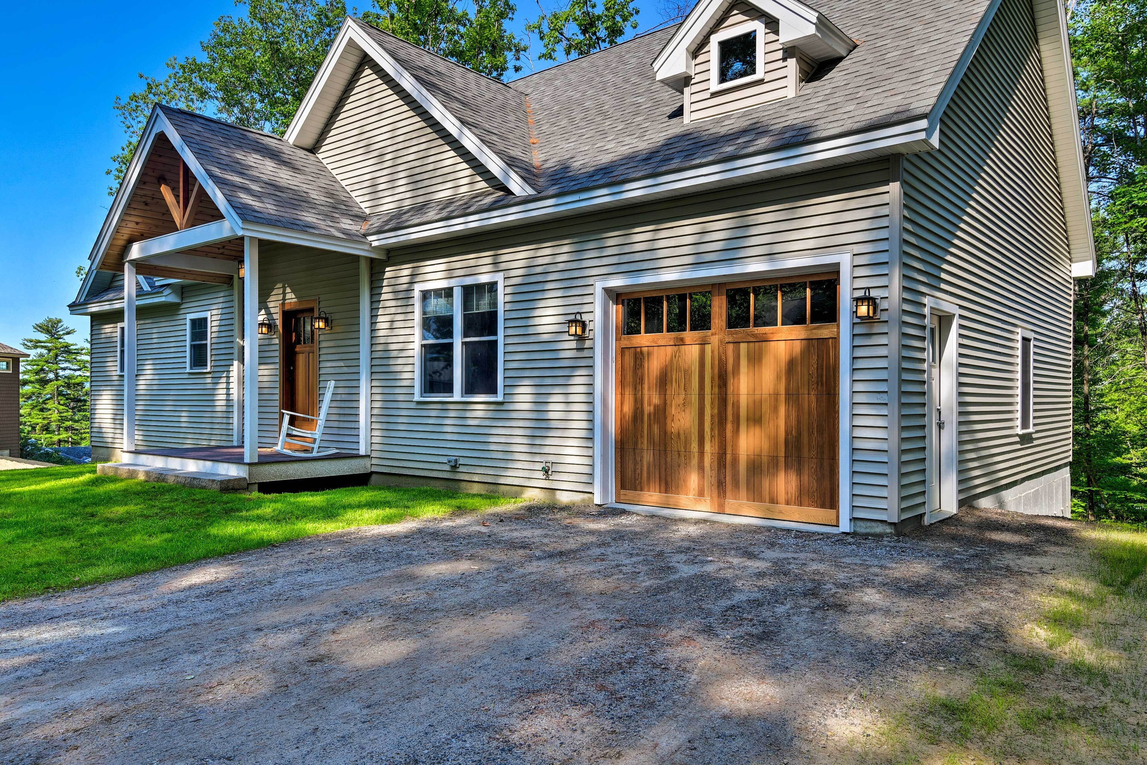 A two-story house with a covered porch, a garage, and a gravel driveway.