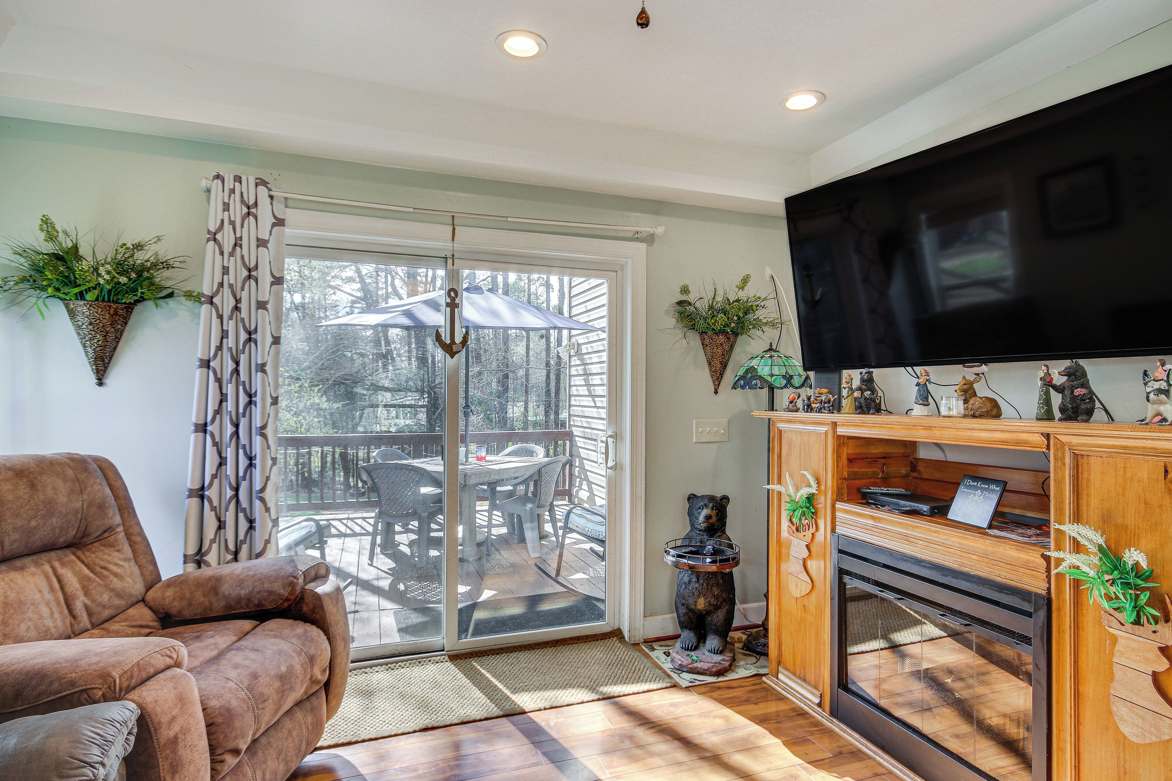 A living room with a sofa, a fireplace, a TV, and a sliding glass door leading to an outdoor patio.