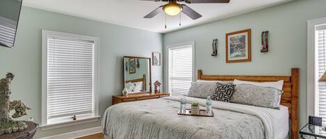 Une chambre à coucher comprenant un lit, des tables de chevet, un ventilateur de plafond et une commode.