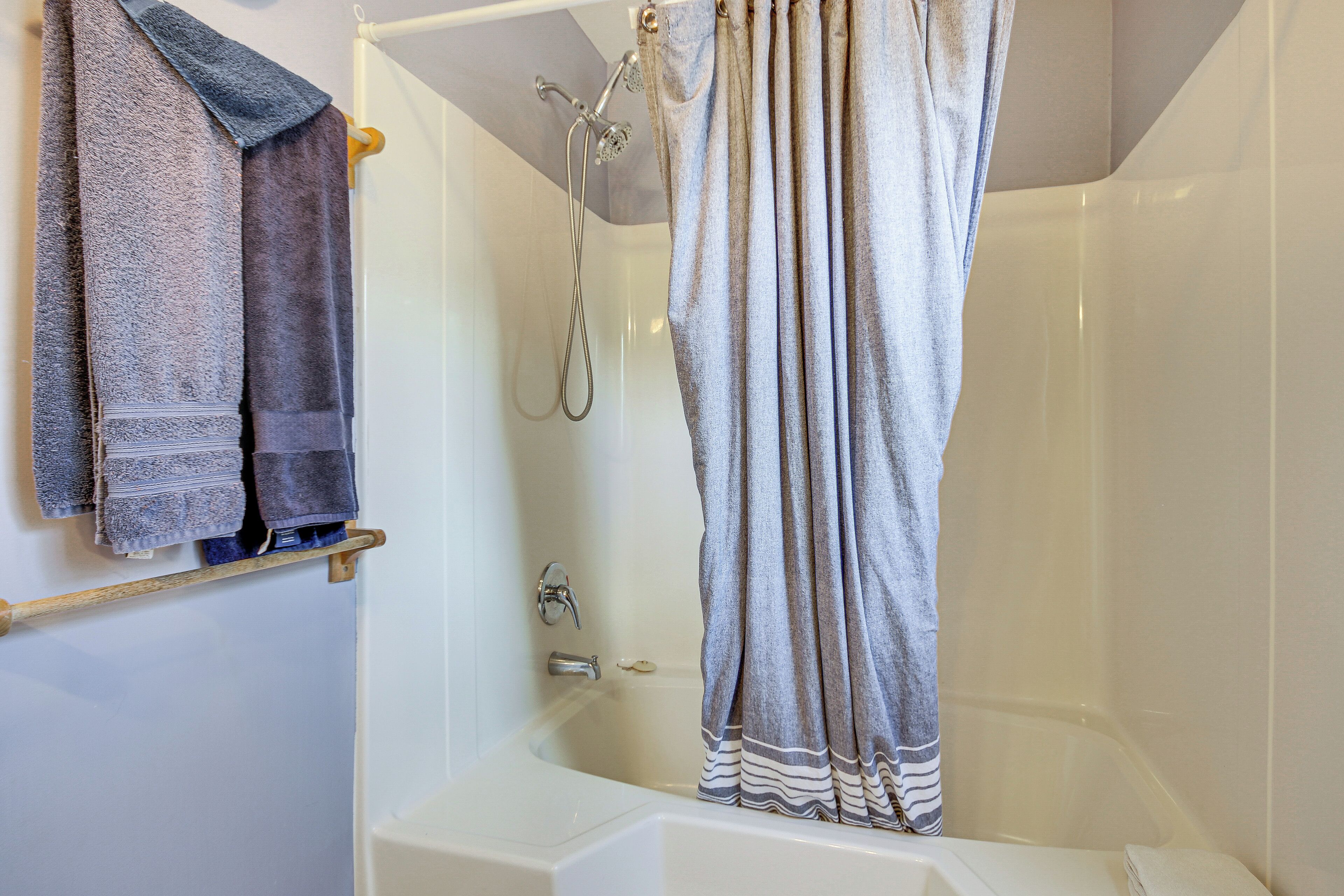 A bathroom with a bathtub, a shower, and a towel rack with multiple towels.