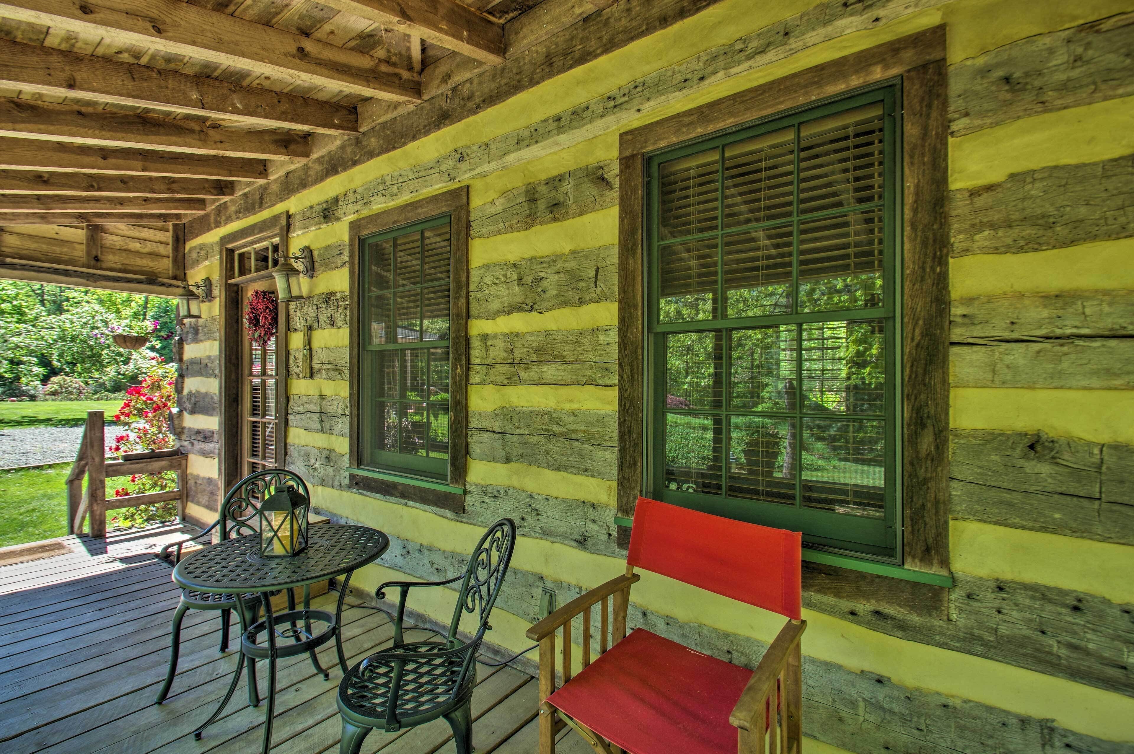 A wooden cabin with a porch, a table, and two chairs.