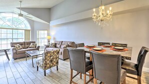 A spacious living area with a dining table, leather chairs, a patterned armchair, and a chandelier. - Laguna Bay Resort Condo ~ 8 Mi to Disney! (Kissimmee)