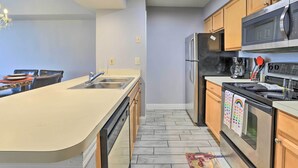 A modern kitchen with a large island, stainless steel appliances, and wooden cabinets. - Laguna Bay Resort Condo ~ 8 Mi to Disney! (Kissimmee)