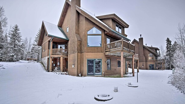 Eine große Holzhütte mit mehreren Balkonen und einer verschneiten Landschaft.