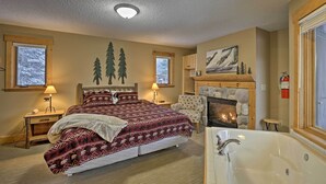 Ein Schlafzimmer mit einem großen Bett, einem Kamin, einem Steinofen, einem Fenster und einer Badewanne.