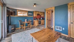 A cozy kitchen with wooden cabinets, a built-in stove, and a dining area with a table and chairs. - Slopeside Burke Mountain Condo w/ Fireplace! (East Burke)