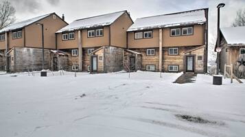 A multi-story building with a snow-covered ground, featuring a mix of wooden and brick exteriors, and a central entrance with a small porch.