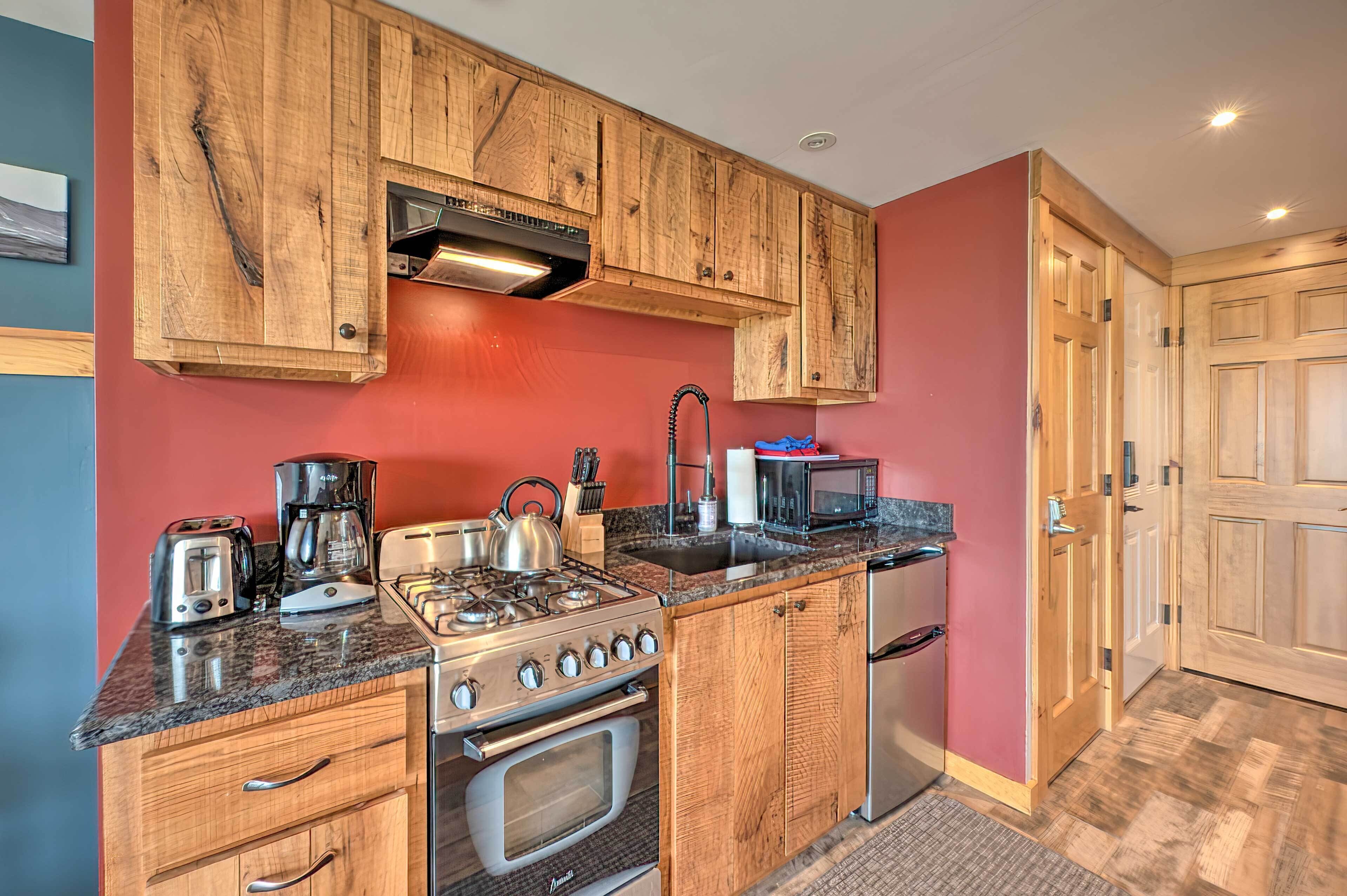 A kitchen with wooden cabinets, a gas stove, a microwave, and a toaster.