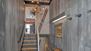 A wooden staircase with a bench at the bottom, a sign on the wall, and a ceiling light fixture. - Slopeside Burke Mountain Condo w/ Fireplace! (East Burke)