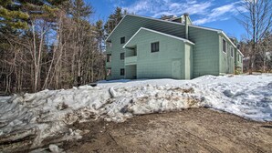 A two-story house with a green exterior, surrounded by a snowy landscape and leafless trees. - Penthouse Ski Unit ~ 1 Mi to Attitash Mountain! (Bartlett)