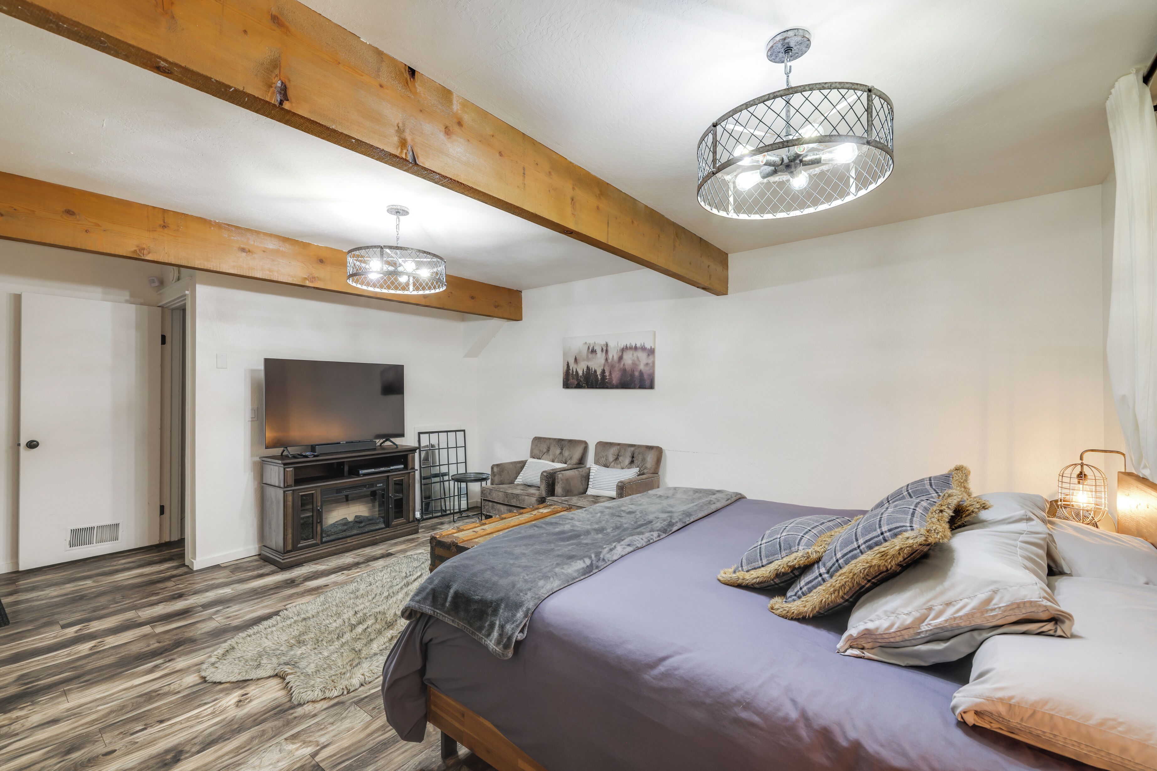 Un dormitorio con una cama grande, televisión, chimenea y vigas de madera.