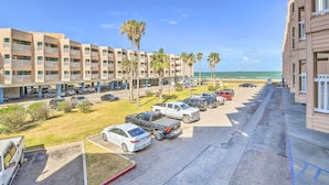 Ein mehrstöckiges Hotel mit Parkplatz, mehreren Autos und Palmen.