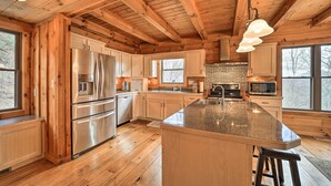 A spacious kitchen with wooden beams, stainless steel appliances, and large windows. - Decks & Mountain Views: Waynesville Getaway! (Waynesville)