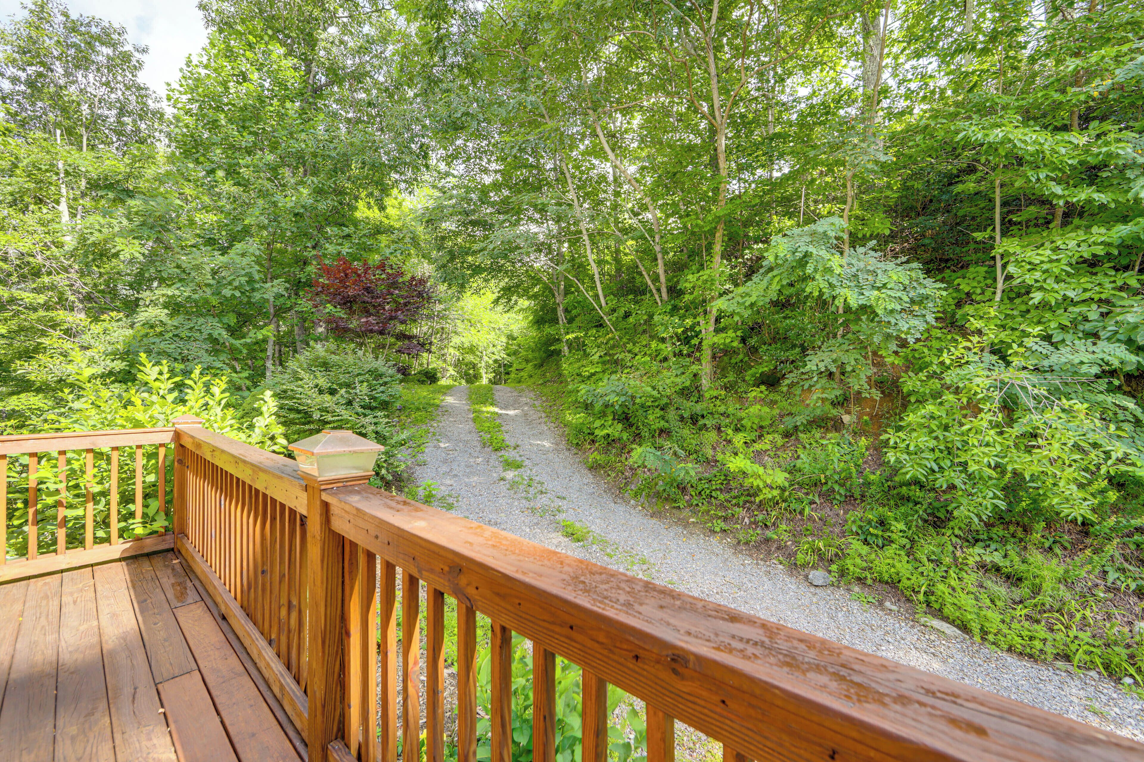 Une terrasse en bois avec un chemin de gravier menant à une zone boisée.