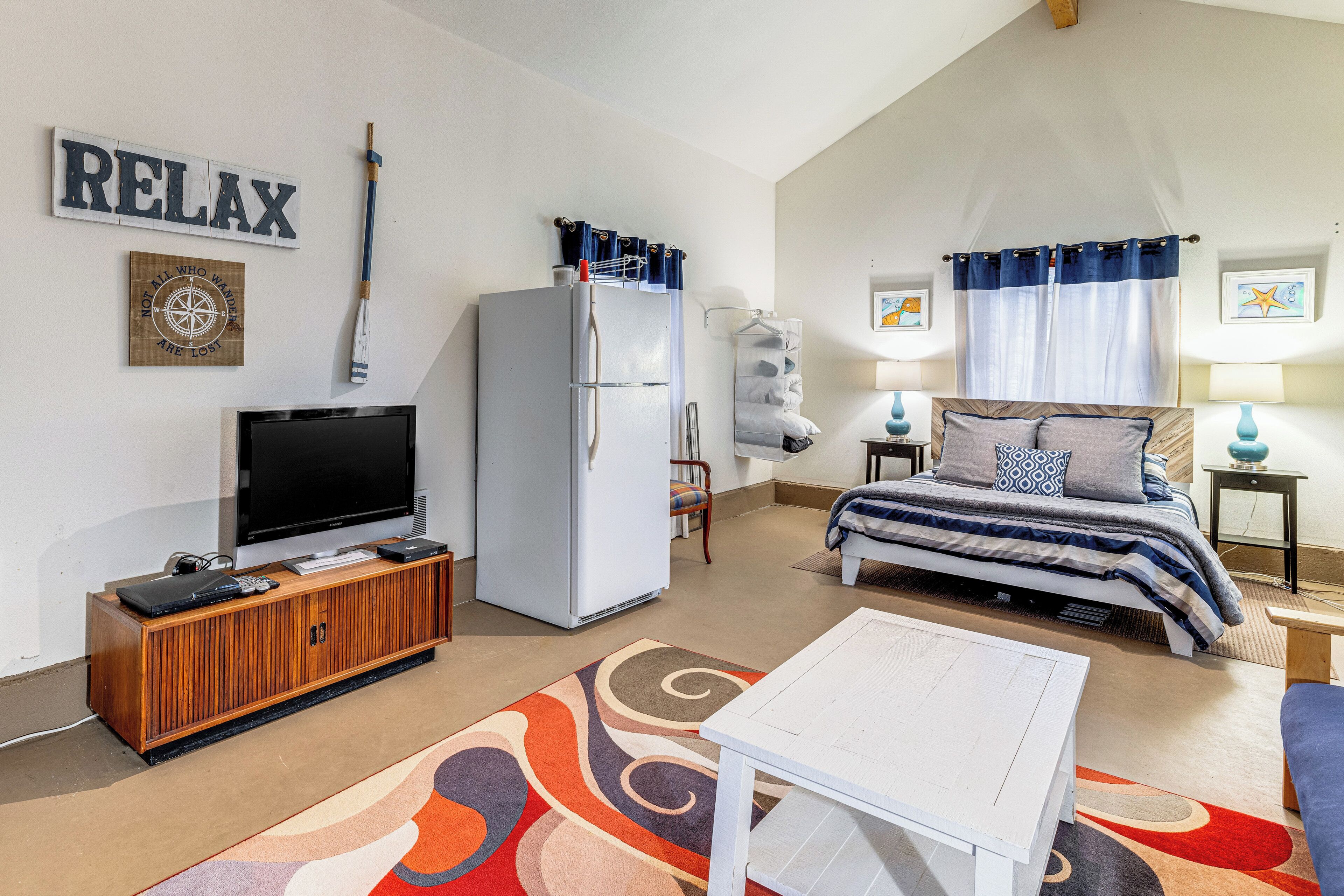 A cozy room with a bed, a TV, a refrigerator, and a wooden cabinet.