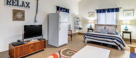 A cozy room with a bed, a TV, a refrigerator, and a wooden cabinet.