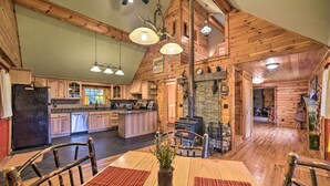 A spacious kitchen with wooden cabinets, a central island, and a dining area with a table and chairs. - Lovely Fort Ann Lodge - 10 Mi to Lake George! (Fort Ann)
