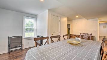 A dining room with a large table, wooden chairs, a window with blinds, and a door.