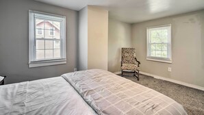 A bedroom with a bed, two windows, a chair, and a ceiling light fixture. - Family-friendly Millville Home < 8 Mi to Town (Millville)