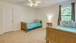 A bedroom with a bed, a ceiling fan, a window with curtains, and a door. - Private Pool: Spacious & Secluded Magnolia Cottage (Magnolia)