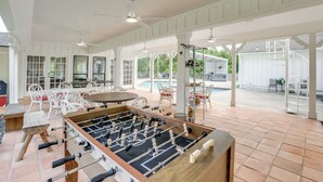 A spacious indoor area with a foosball table, white furniture, and a pool in the background. - Private Pool: Spacious & Secluded Magnolia Cottage (Magnolia)