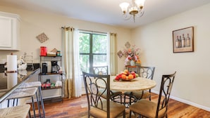 A dining area with a round table, four chairs, a coffee machine, and a window with curtains. - Private Pool: Spacious & Secluded Magnolia Cottage (Magnolia)